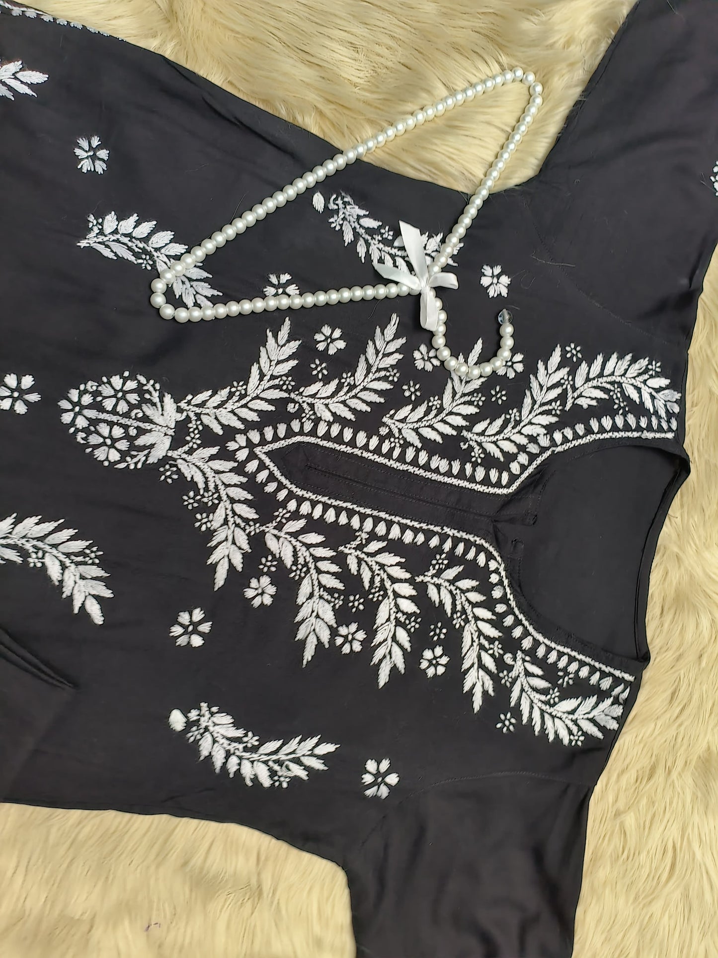 Black rayon chikankari kurta and palazzo set with white hand embroidery displayed on fur background