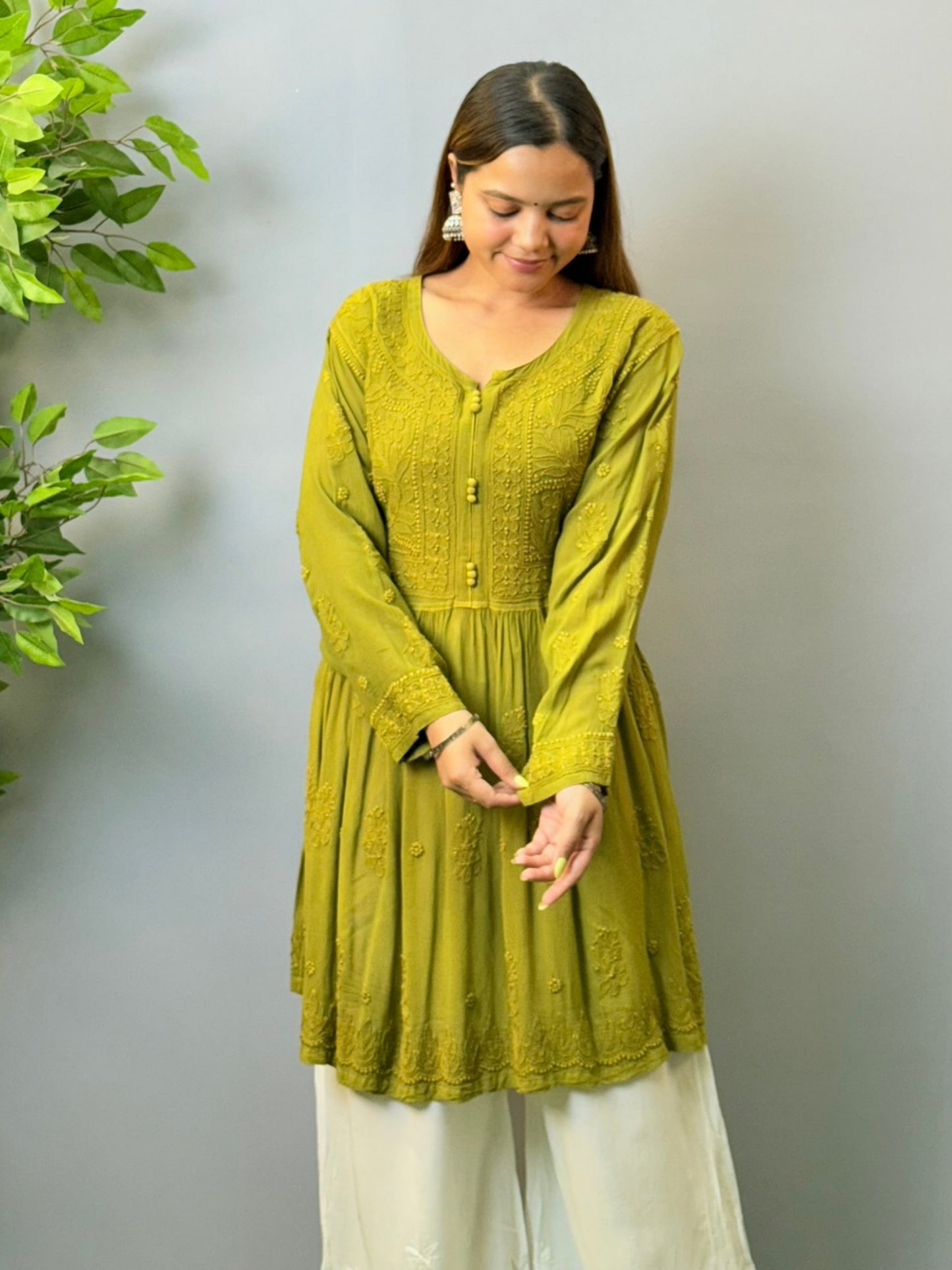 Woman wearing mustard green angrakha-style short chikankari kurta in viscose fabric with flared silhouette