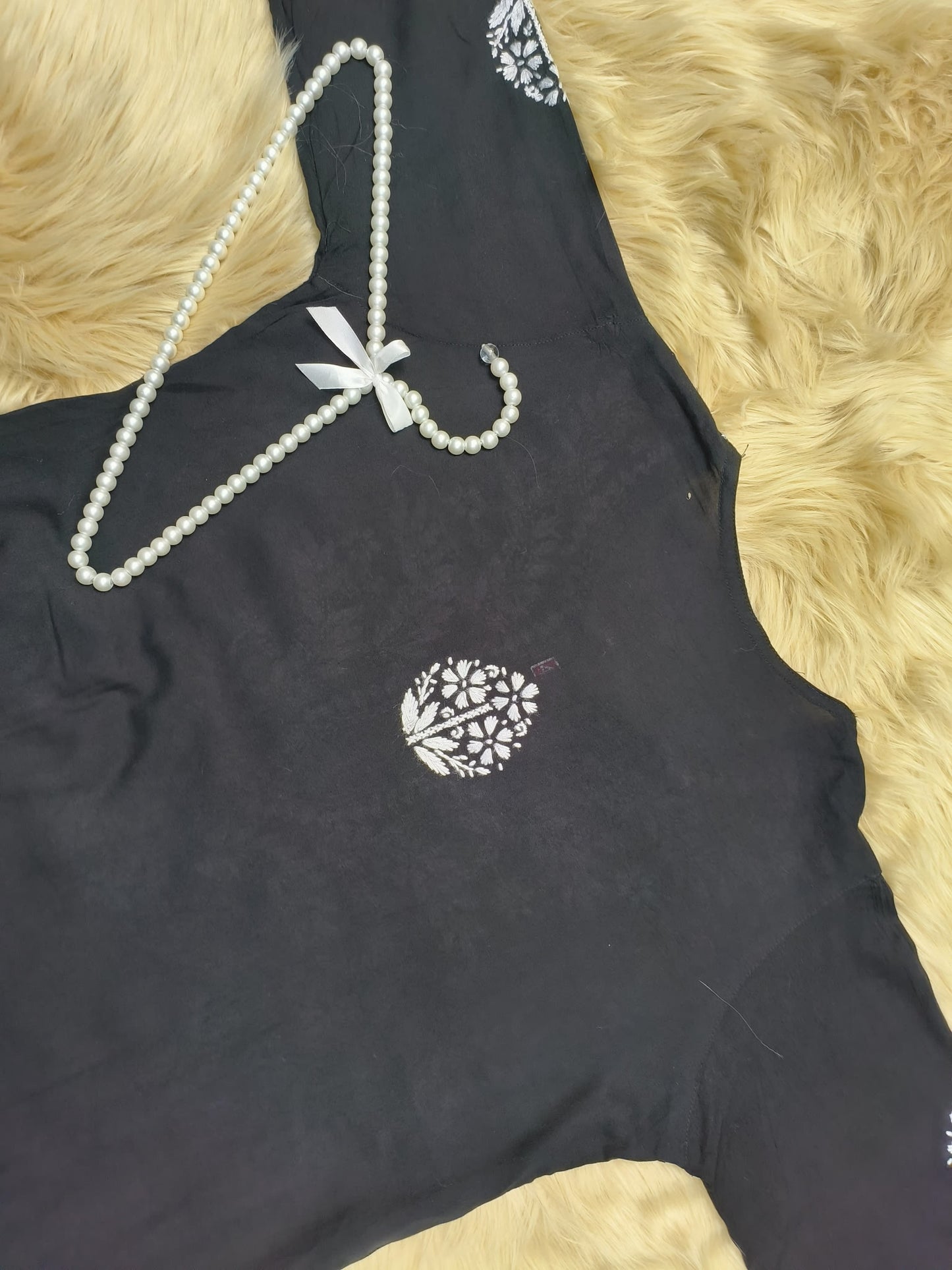Black rayon chikankari kurta and palazzo set with white hand embroidery displayed on fur background