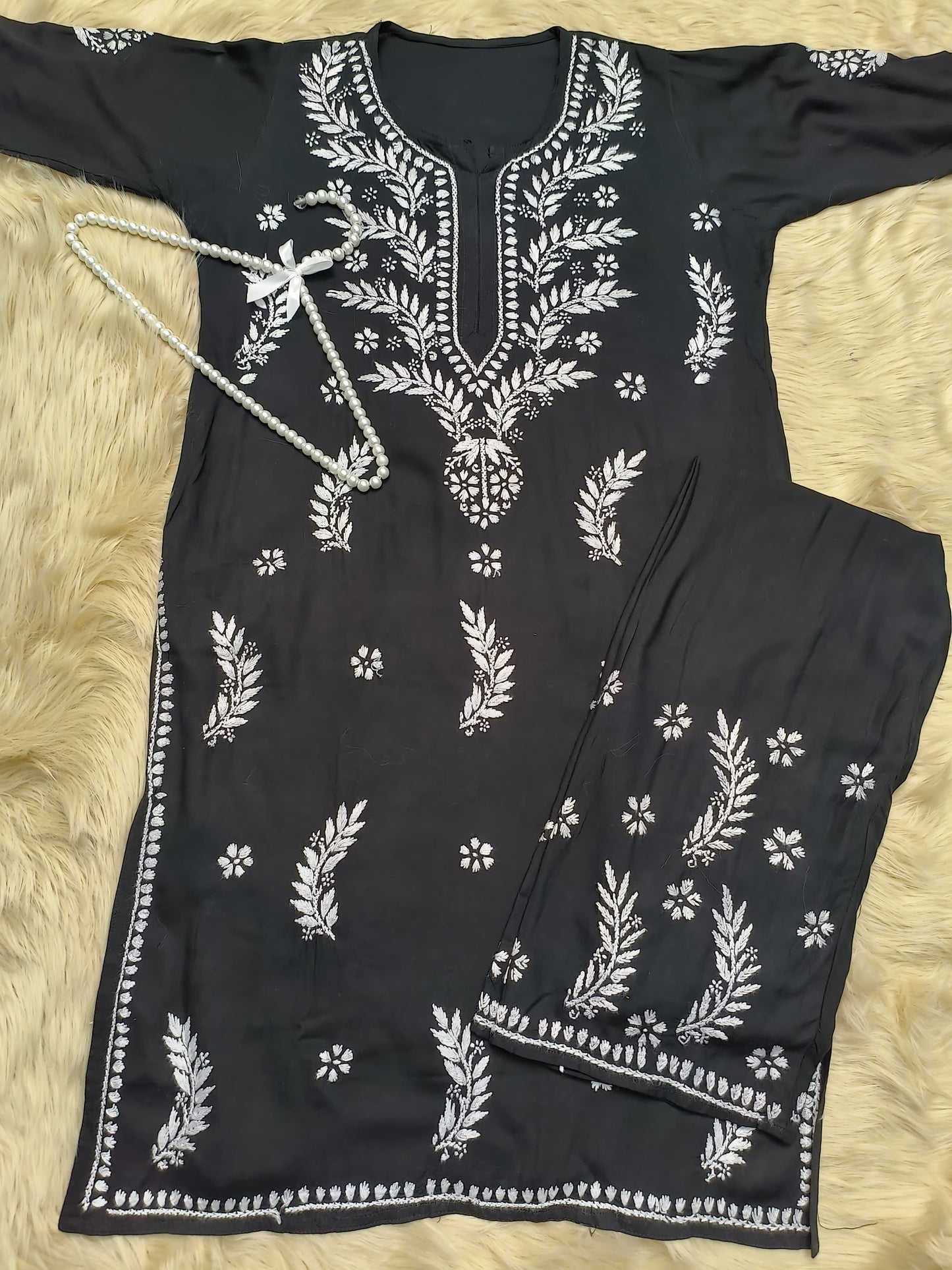 Black rayon chikankari kurta and palazzo set with white hand embroidery displayed on fur background