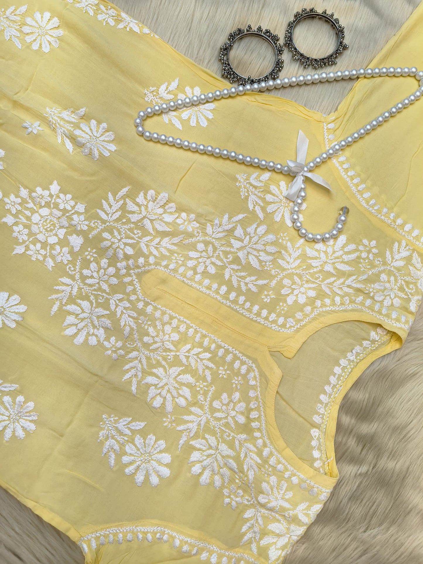 Sunshine yellow modal chikankari kurta with white hand embroidery displayed with pearl hanger and silver bangles