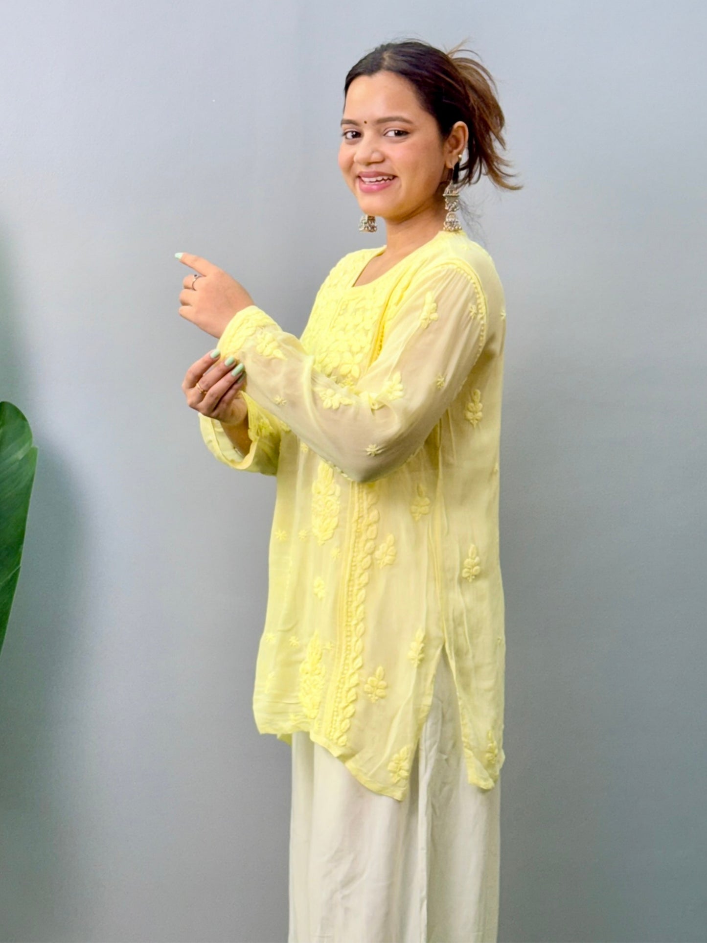 Woman wearing lemon yellow Chikankari short kurta with 3D hand embroidery in viscose fabric and translucent texture