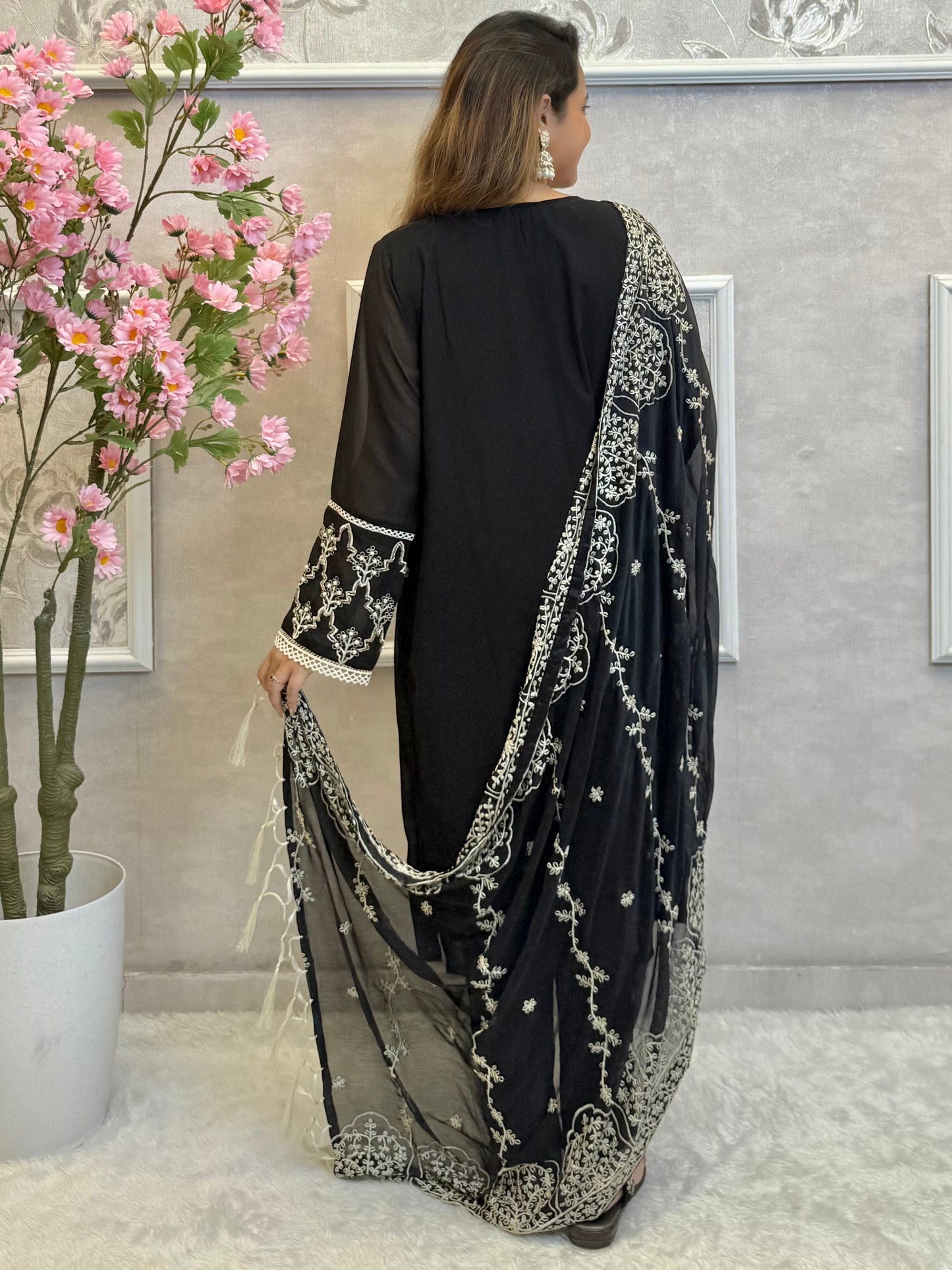 Model wearing a black georgette kurta with lycra stretchable pants and embroidered georgette dupatta with tassels – Designer Wear Collection.