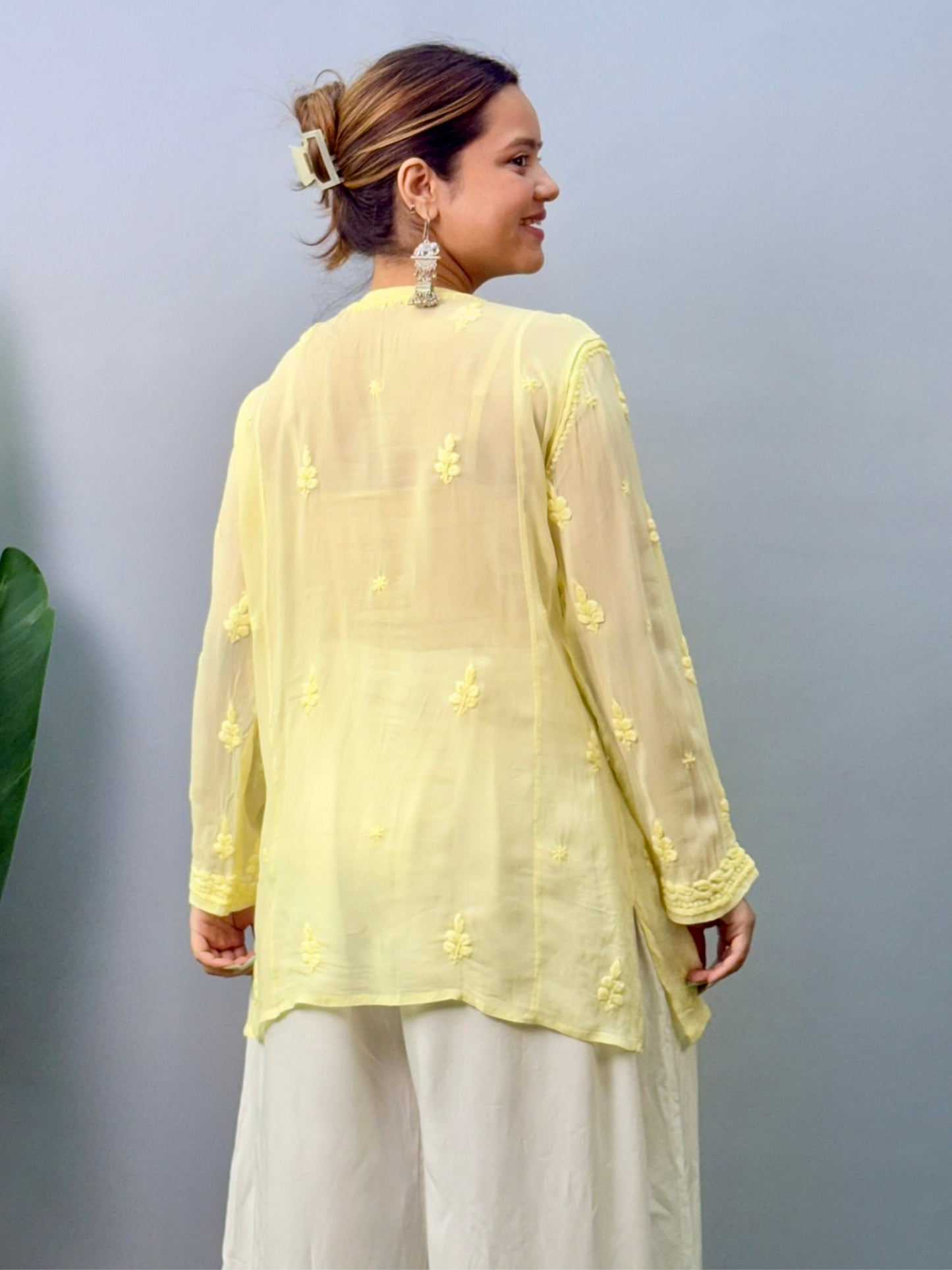 Woman wearing lemon yellow Chikankari short kurta with 3D hand embroidery in viscose fabric and translucent texture