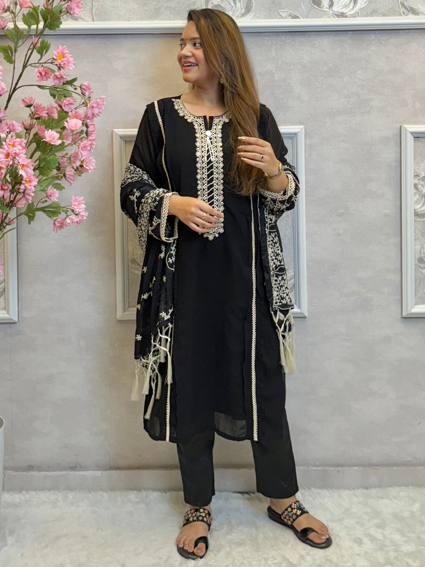 Model wearing a black georgette kurta with lycra stretchable pants and embroidered georgette dupatta with tassels – Designer Wear Collection.