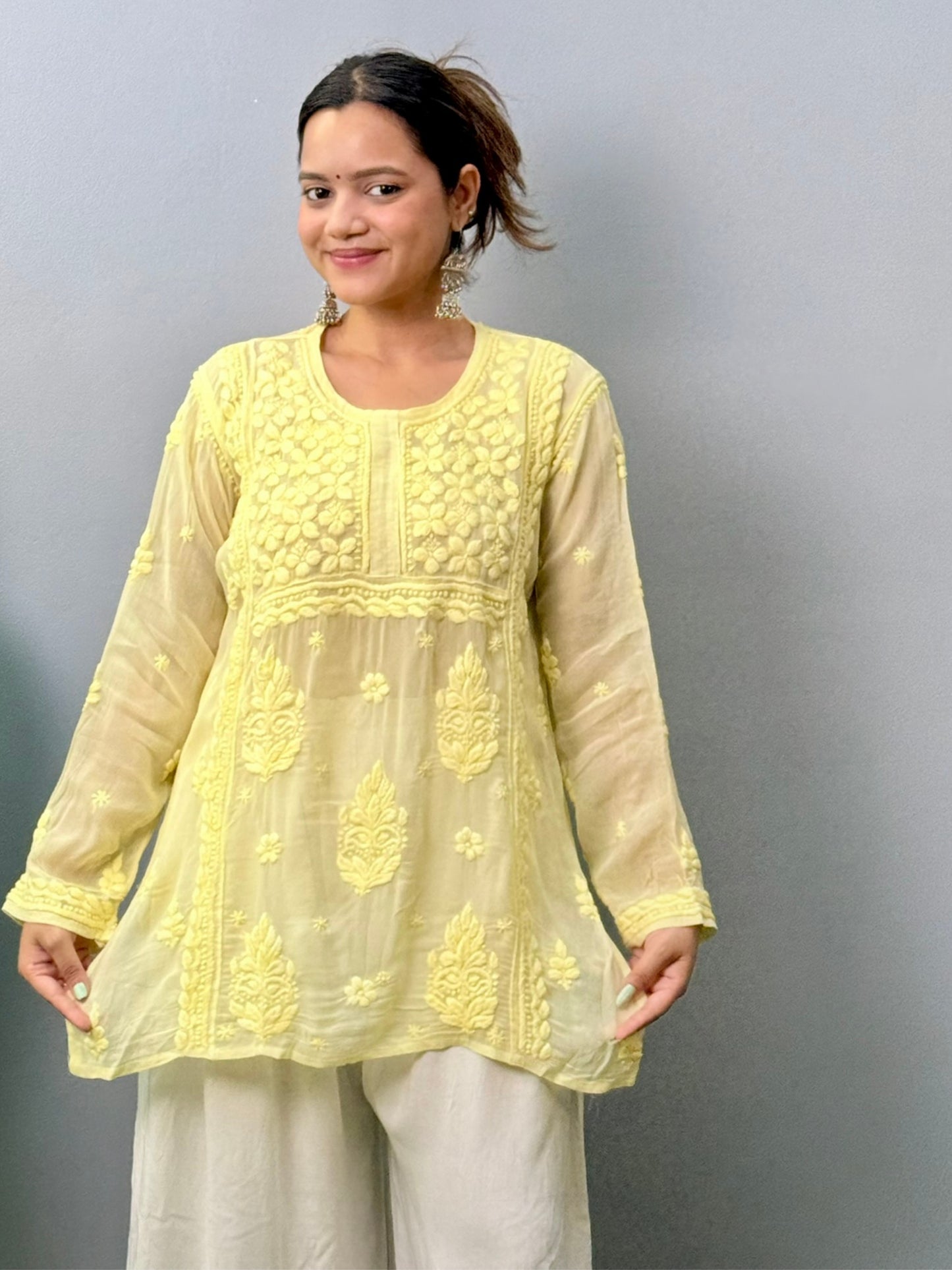 Woman wearing lemon yellow Chikankari short kurta with 3D hand embroidery in viscose fabric and translucent texture