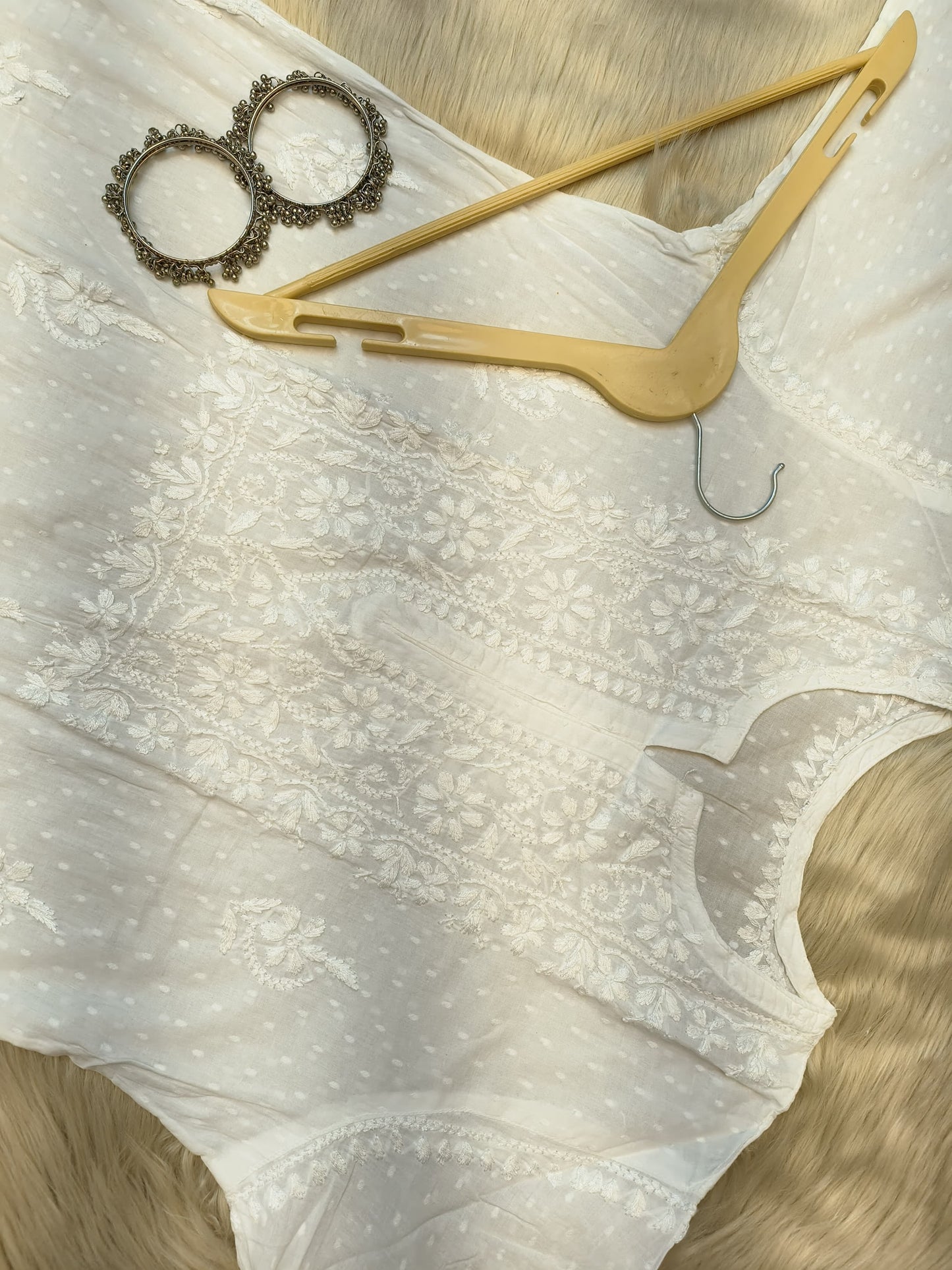 White Chikankari dobby cotton kurta with matching palazzo, bangles and hanger placed on fur background