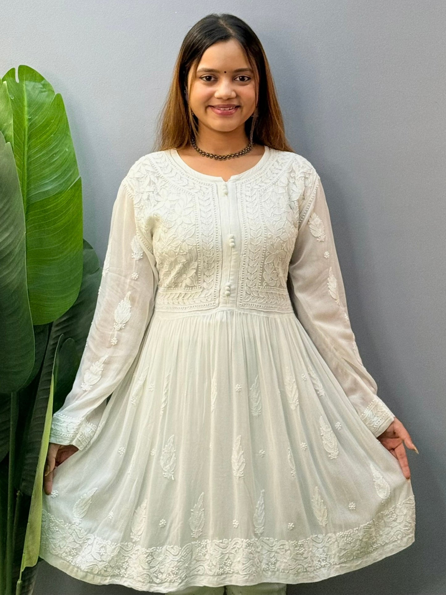 Model wearing a white flared chikankari short kurta with all-over hand embroidery in viscose fabric