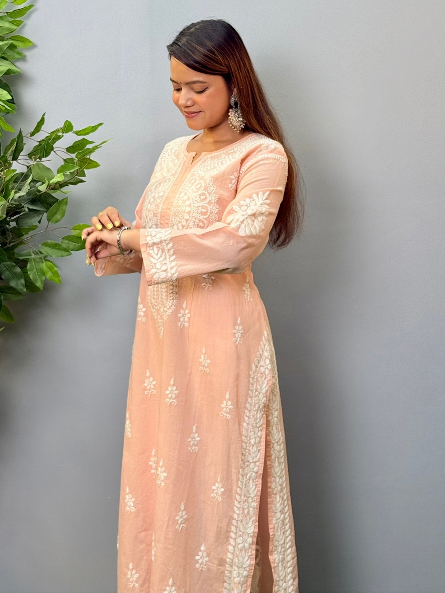 Model wearing a peach pink cotton chikankari kurta with delicate white hand embroidery