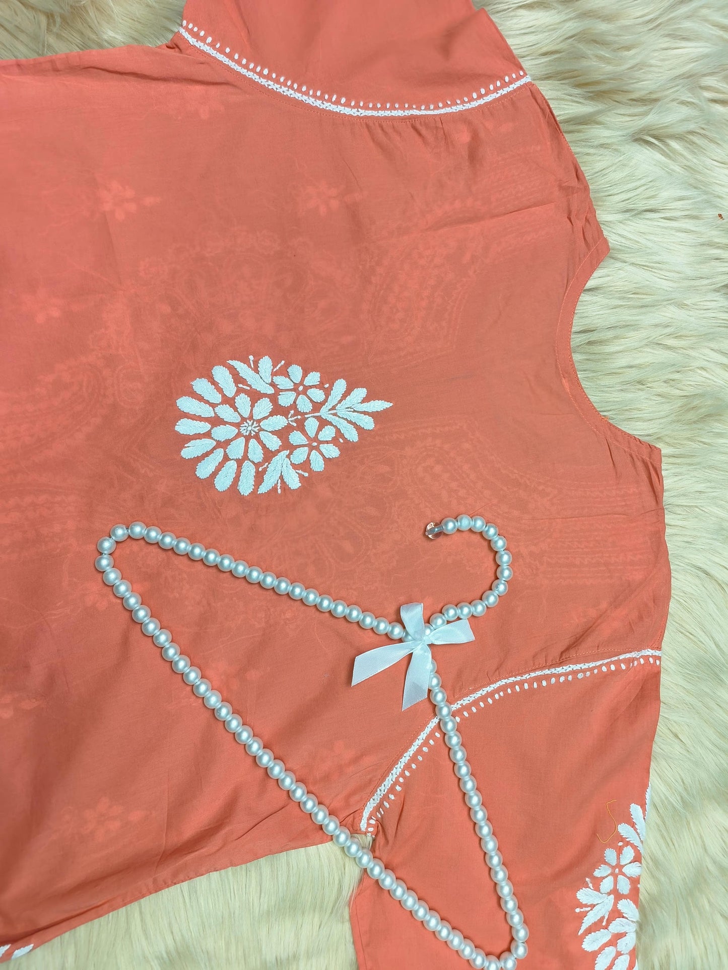 Rust cotton Lucknow Chikankari kurta with white embroidery and pearl hanger on fur background