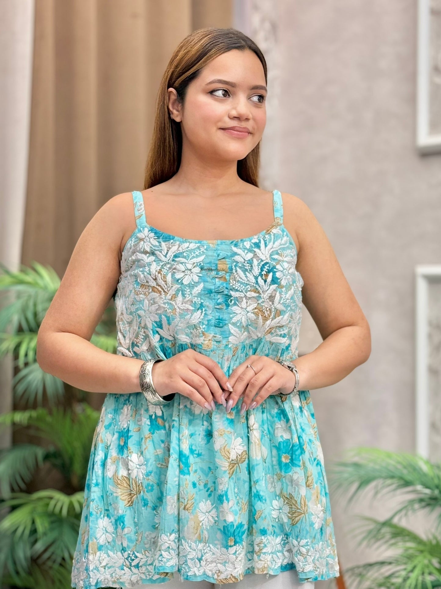 Sleeveless aqua floral printed short chikankari kurta in mulmul fabric with flared hem worn with white pants