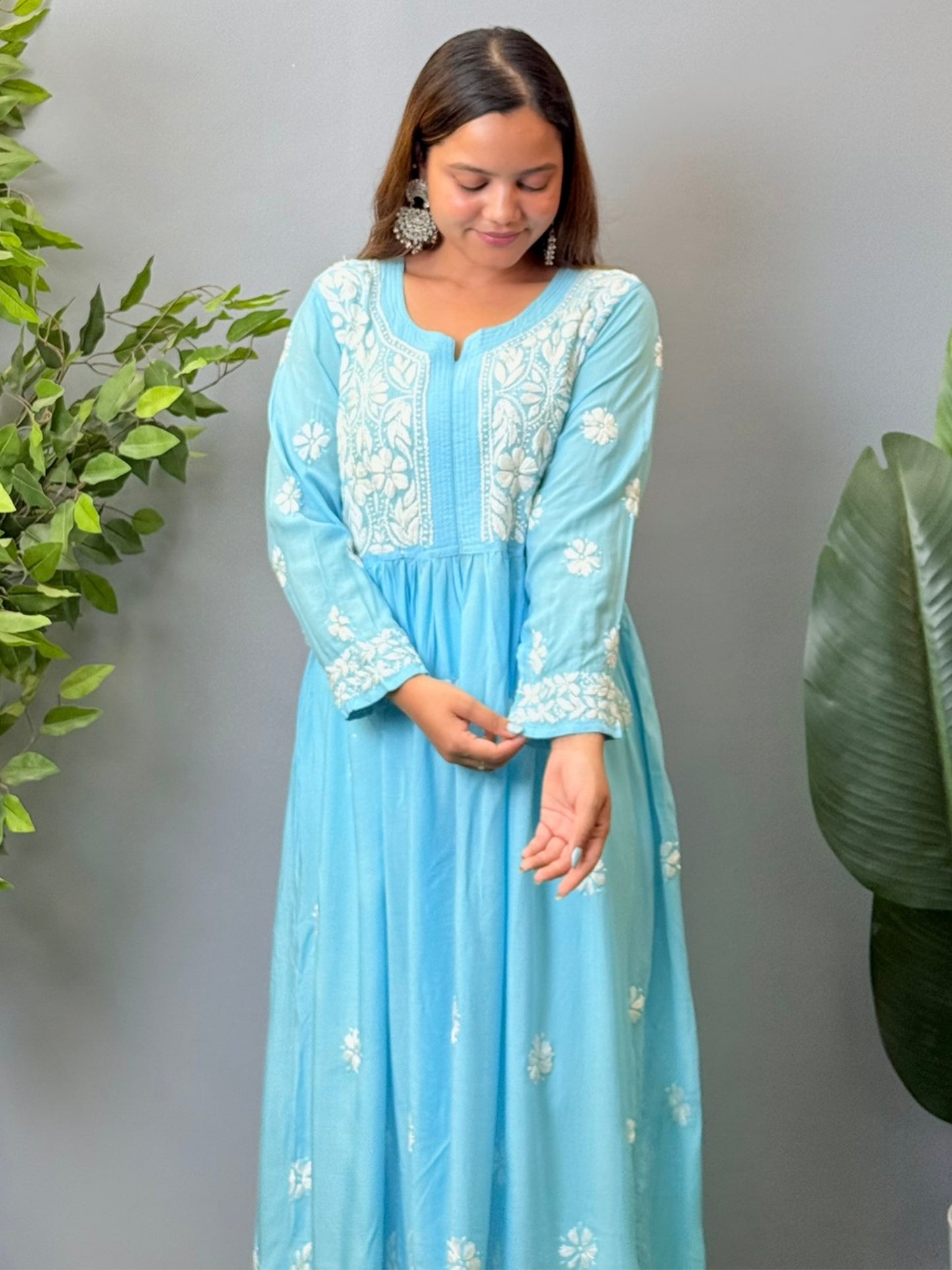 Model wearing a sky blue modal chikankari long frock with white hand embroidery and elegant flared silhouette.