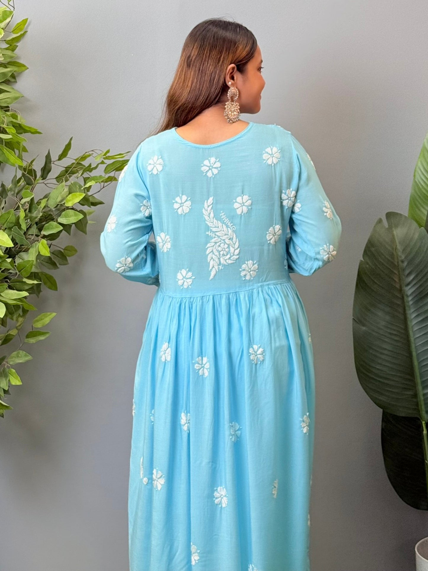 Model wearing a sky blue modal chikankari long frock with white hand embroidery and elegant flared silhouette.