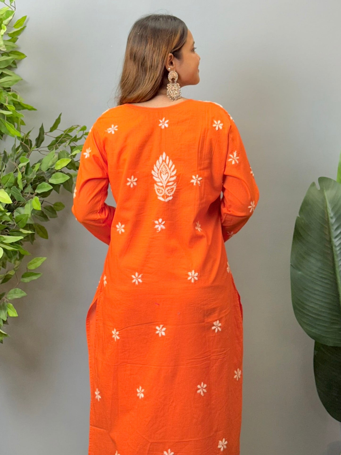 Model wearing a bright orange cotton chikankari kurta with white hand embroidery
