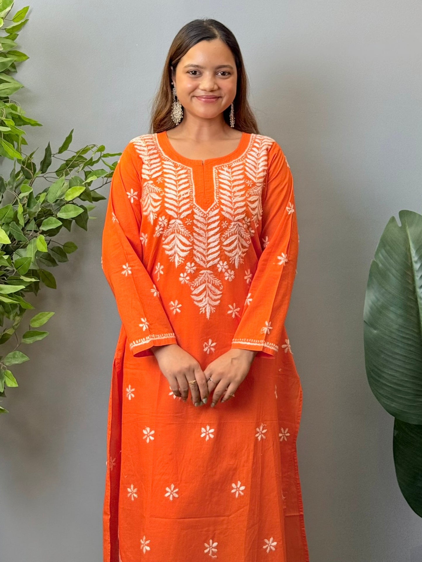 Model wearing a bright orange cotton chikankari kurta with white hand embroidery