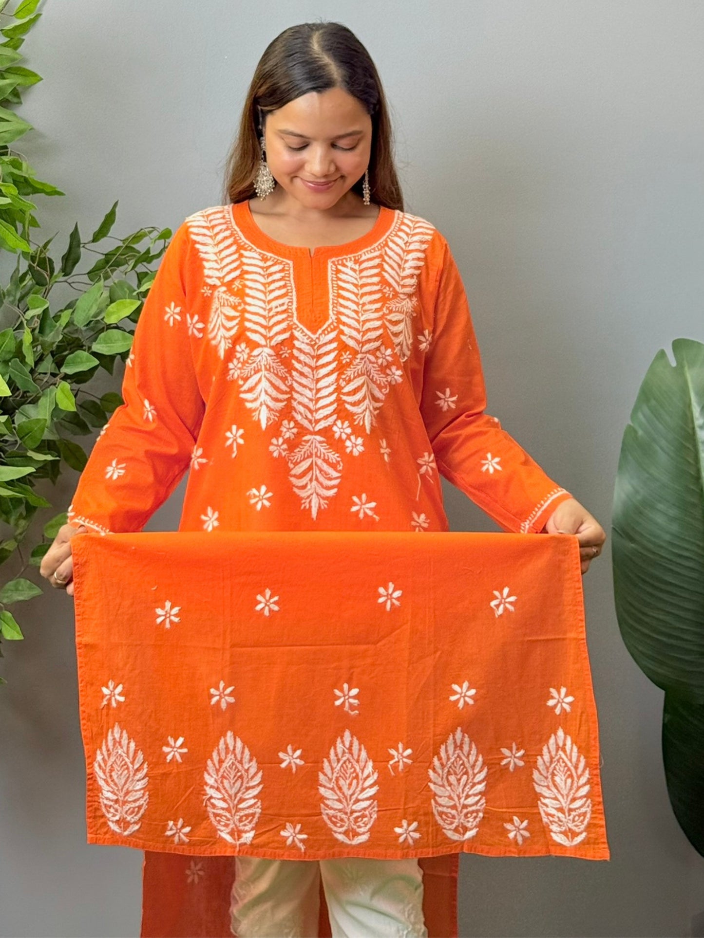 Model wearing a bright orange cotton chikankari kurta with white hand embroidery