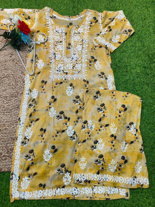 Flat lay of premium mustard yellow floral printed mulmul Lucknowi Chikankari kurta and palazzo set with white embroidery detailing, by R S CHIKANKARI.
