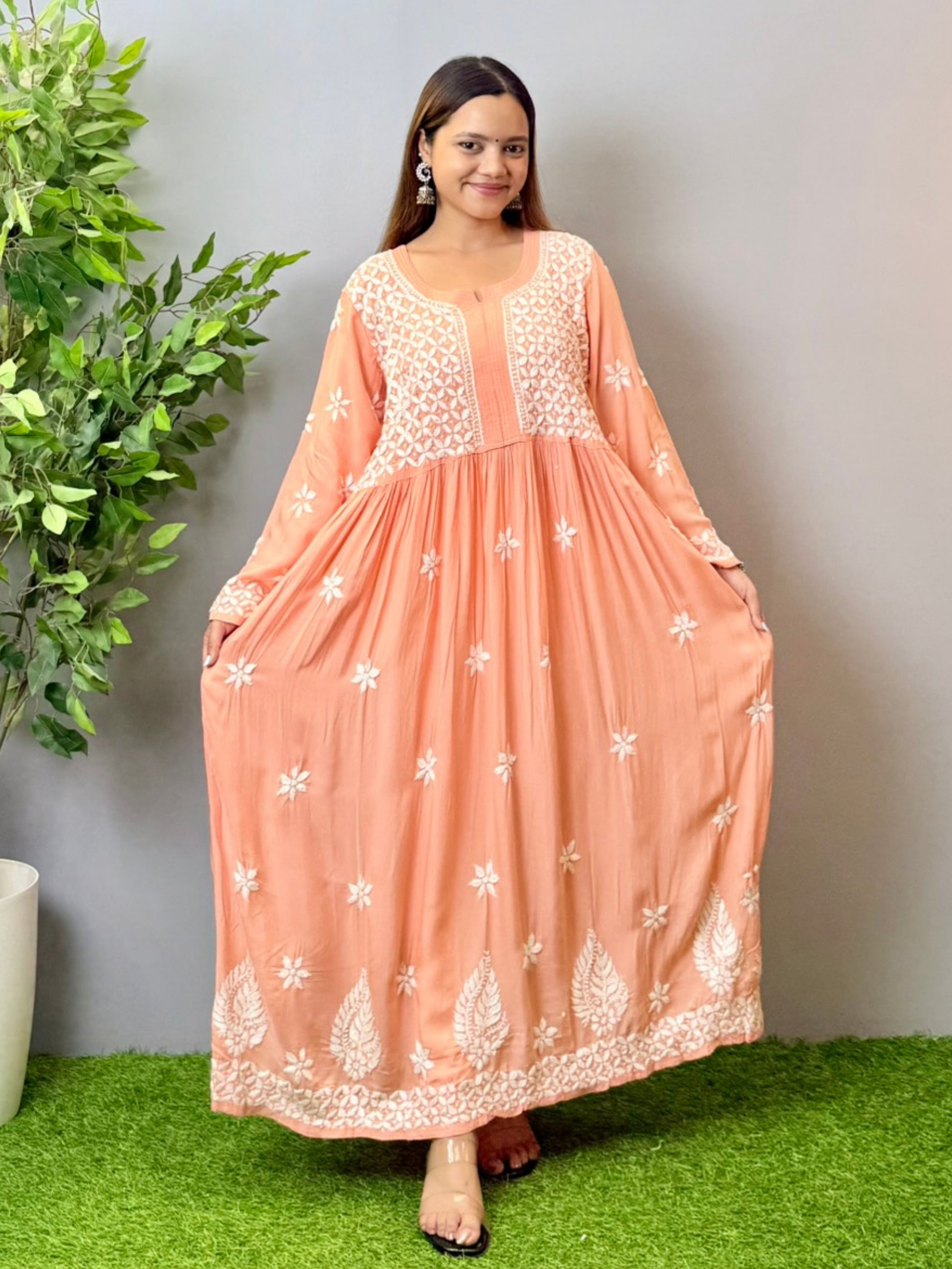 Model wearing a peach Lucknowi chikankari long frock in soft modal fabric with intricate white hand embroidery and a flared silhouette.