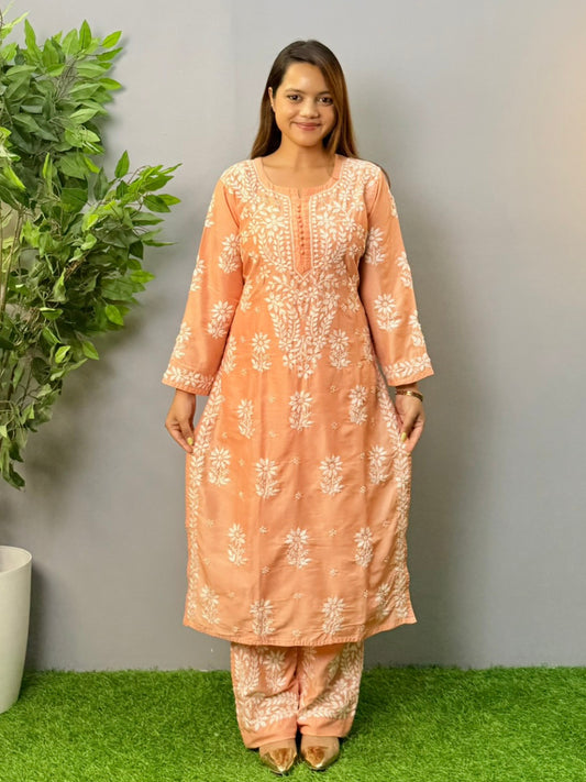 Model wearing a peach muslin chikankari kurta and pant set with white embroidery