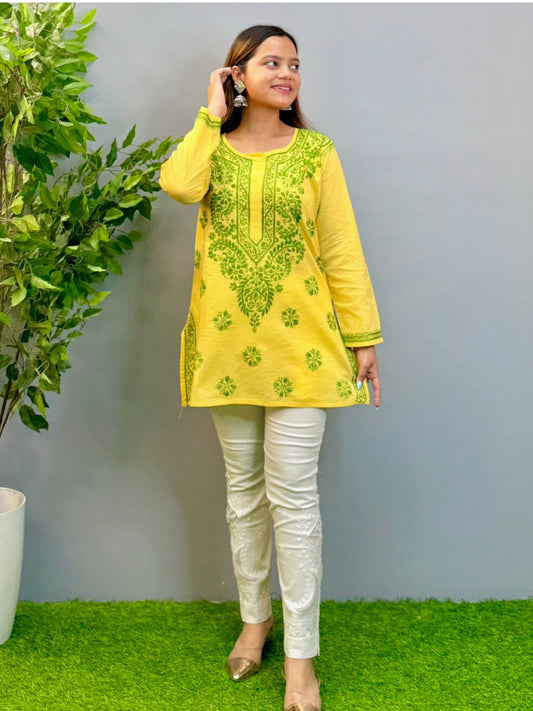 Model wearing bright yellow short cotton chikankari kurta with green contrast embroidery.