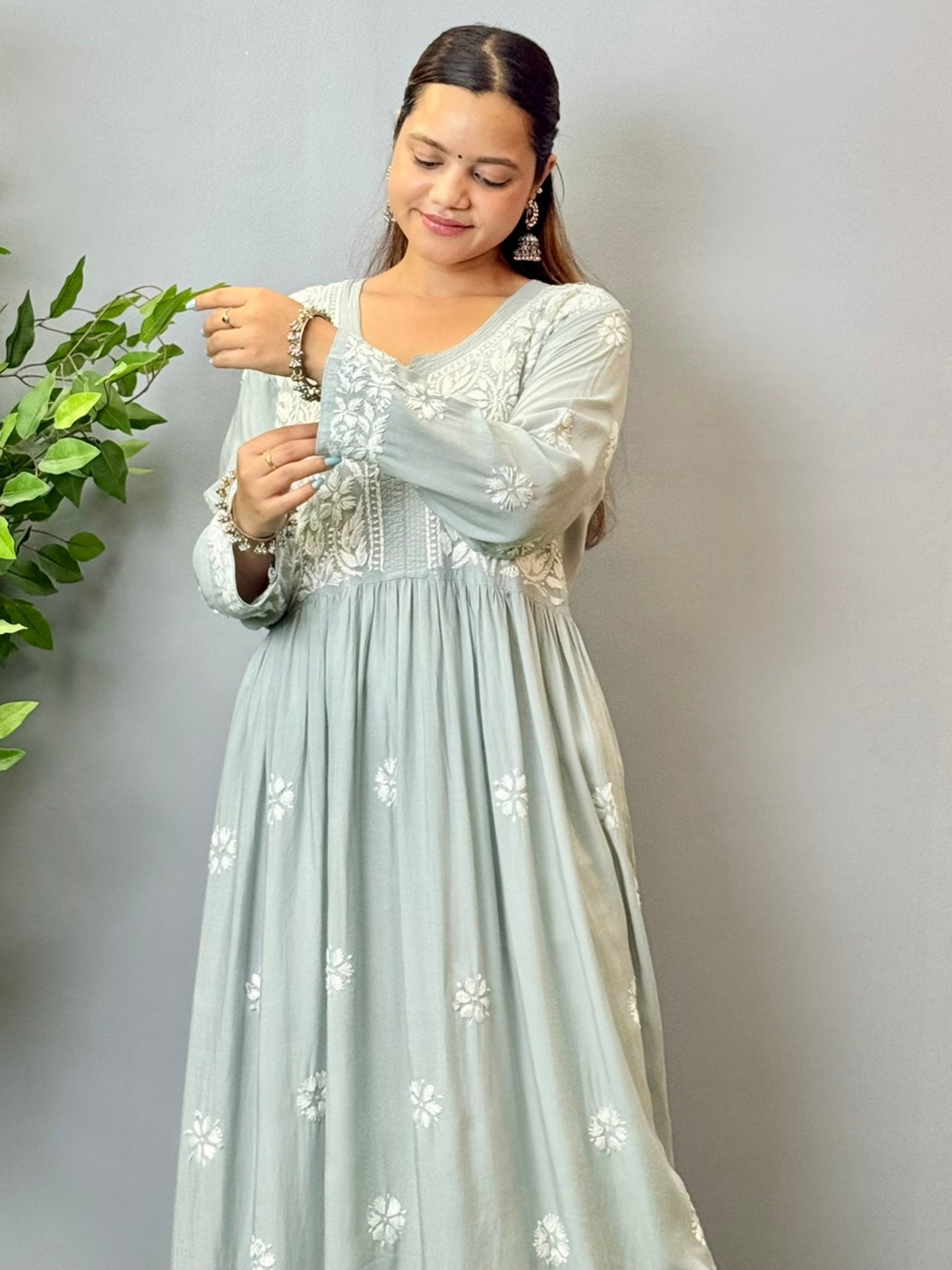 Model wearing a dusty grey Lucknowi chikankari long frock in modal fabric with intricate white hand embroidery and soft flared styling.