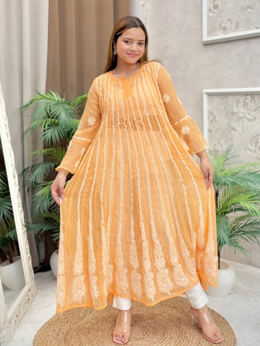 Model wearing a mustard sheer georgette Lucknowi chikankari long frock with heavy flare and fine embroidery, styled for a festive occasion.
