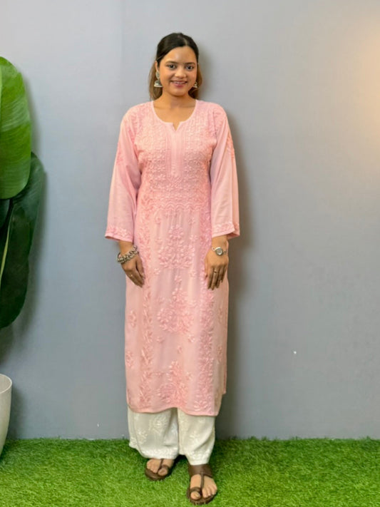 Woman wearing a blush pink modal chikankari kurta with intricate embroidery, paired with white palazzo pants
