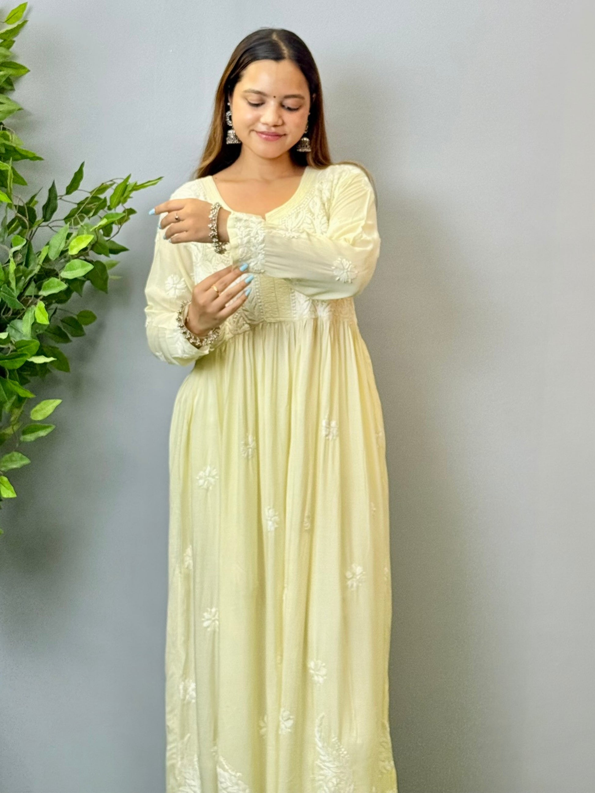 Model wearing an ivory cream Lucknowi chikankari long frock in modal fabric with white hand embroidery and soft flowy drape.