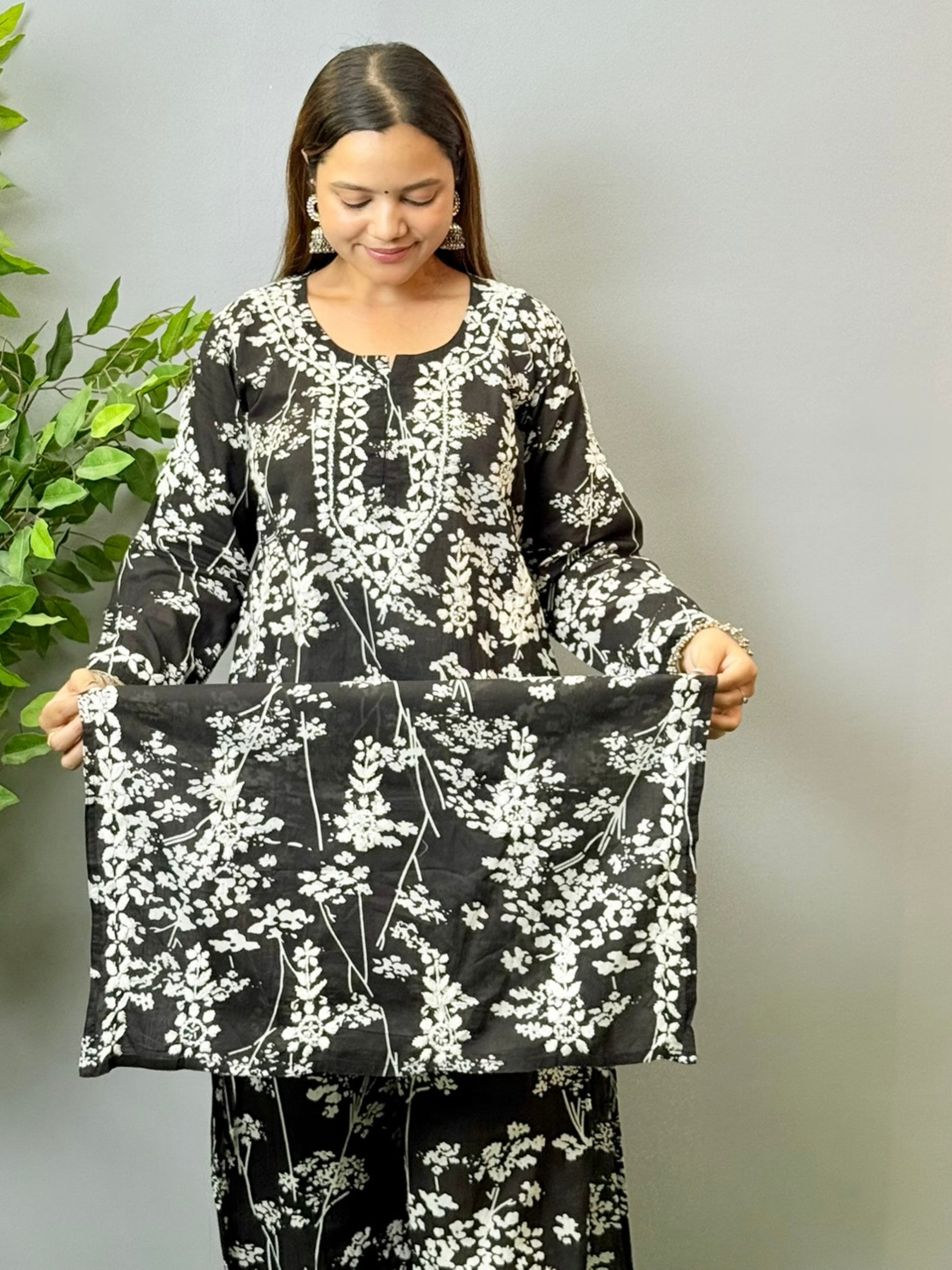 Model wearing a black floral printed Lucknowi chikankari kurta with matching palazzo in mulmul fabric and white embroidery.