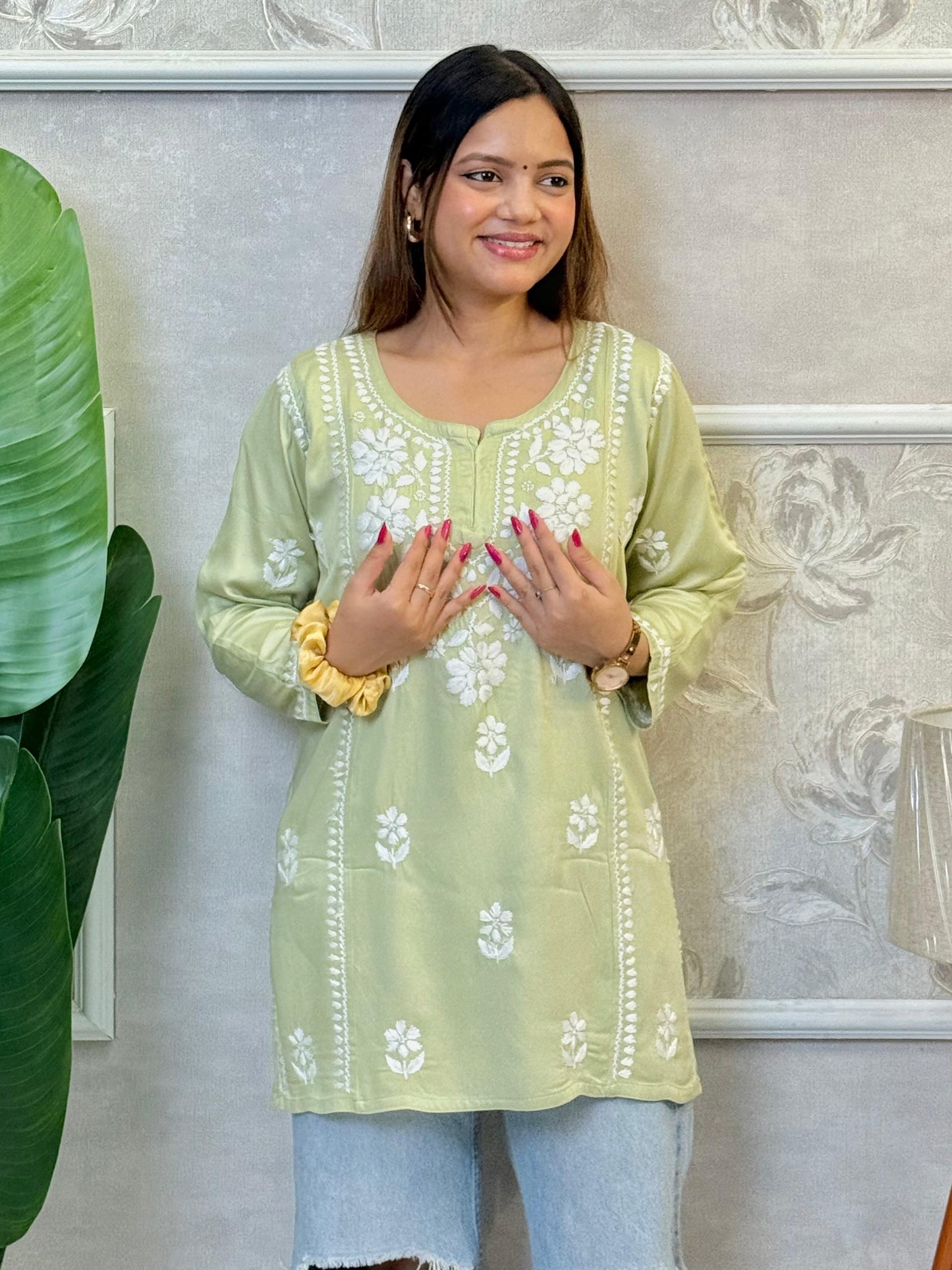 Light green satin short kurta with white Chikankari embroidery, worn with ripped jeans