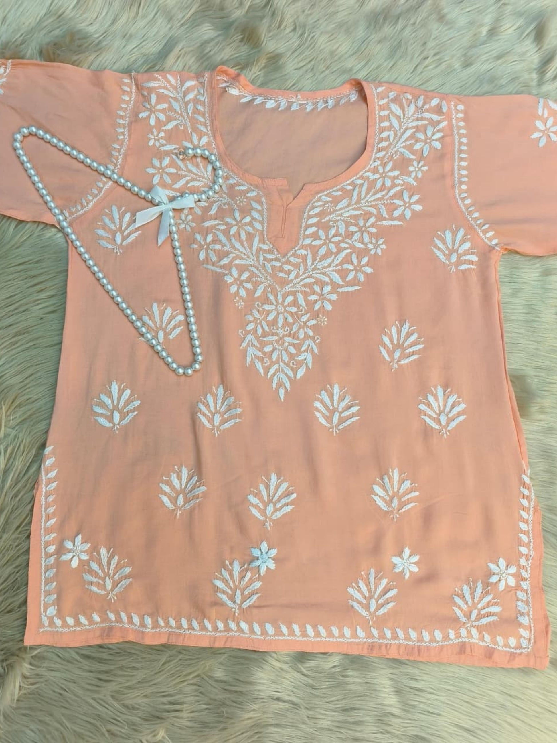 Peach modal short kurta with white hand-embroidered Lucknowi Chikankari design.