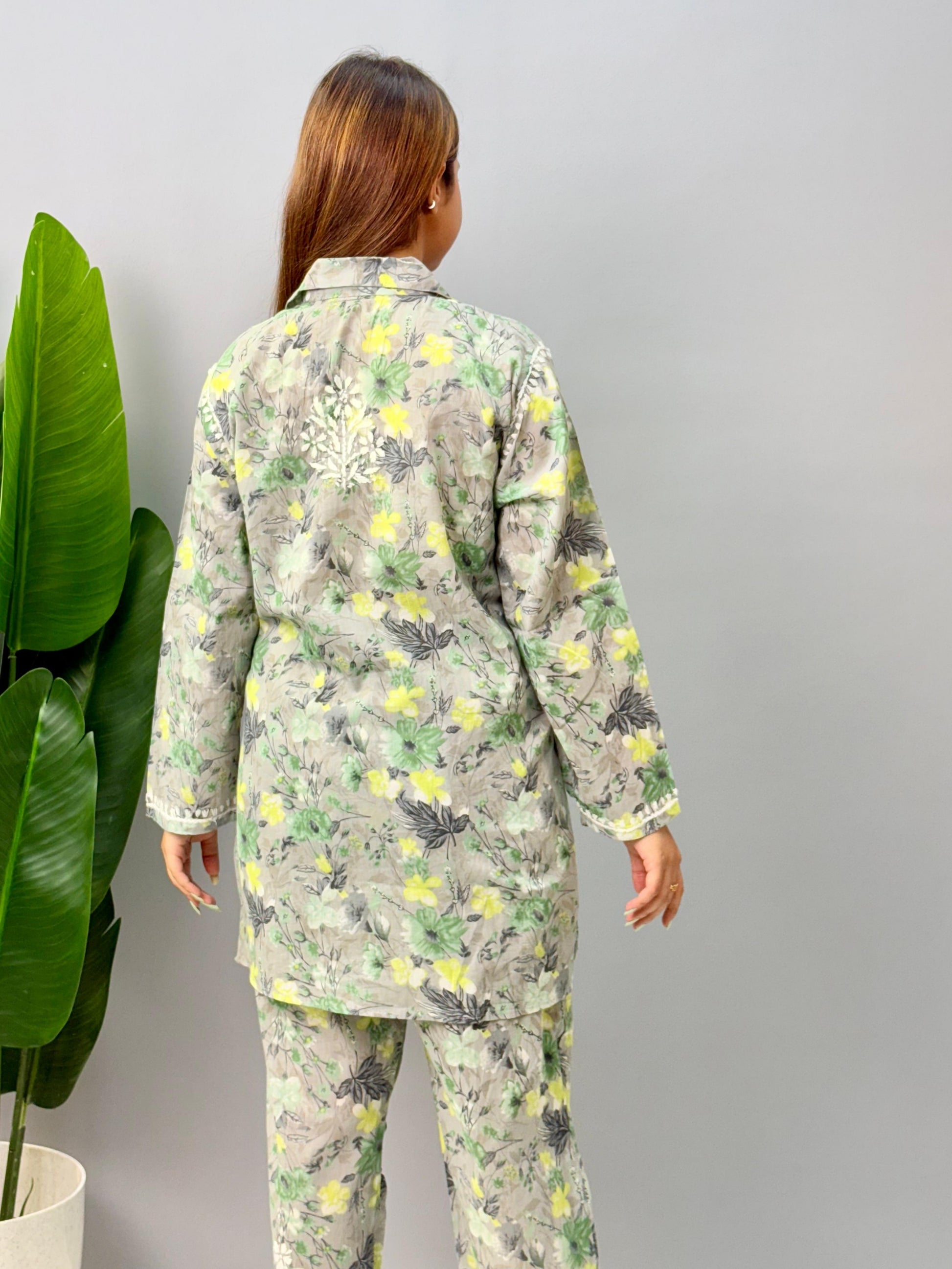 Model wearing a grey printed mulmul chikankari co-ord set with green and yellow floral design, featuring a long shirt-style kurta and matching pants.
