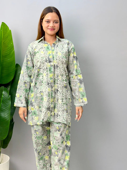 Model wearing a grey printed mulmul chikankari co-ord set with green and yellow floral design, featuring a long shirt-style kurta and matching pants.