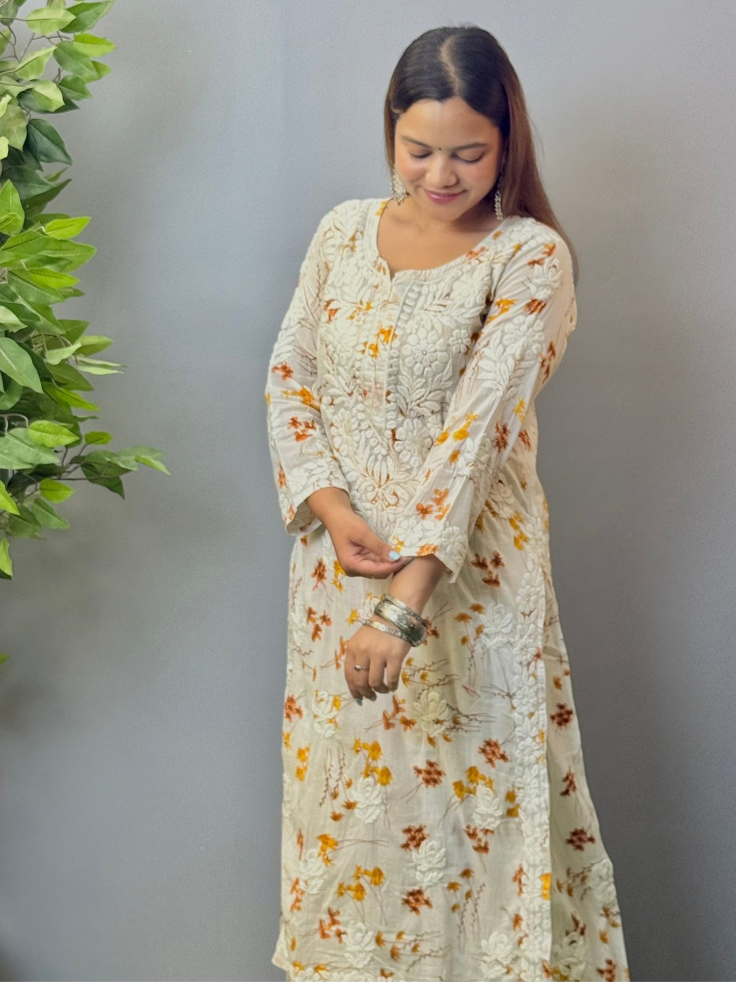 Model wearing ivory mulmul kurta and palazzo set with floral print and 3D hand embroidery.