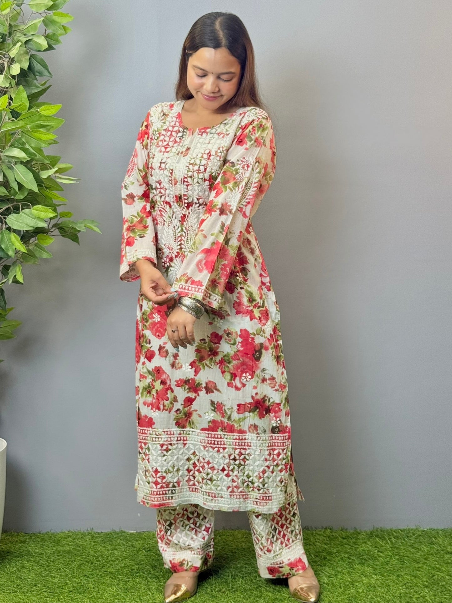 Model wearing floral white mulmul Lucknow chikankari kurta and pant set with pink rose print and white embroidery.