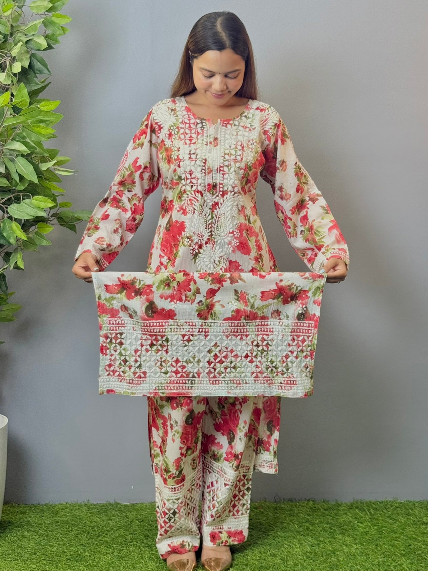 Model wearing floral white mulmul Lucknow chikankari kurta and pant set with pink rose print and white embroidery.