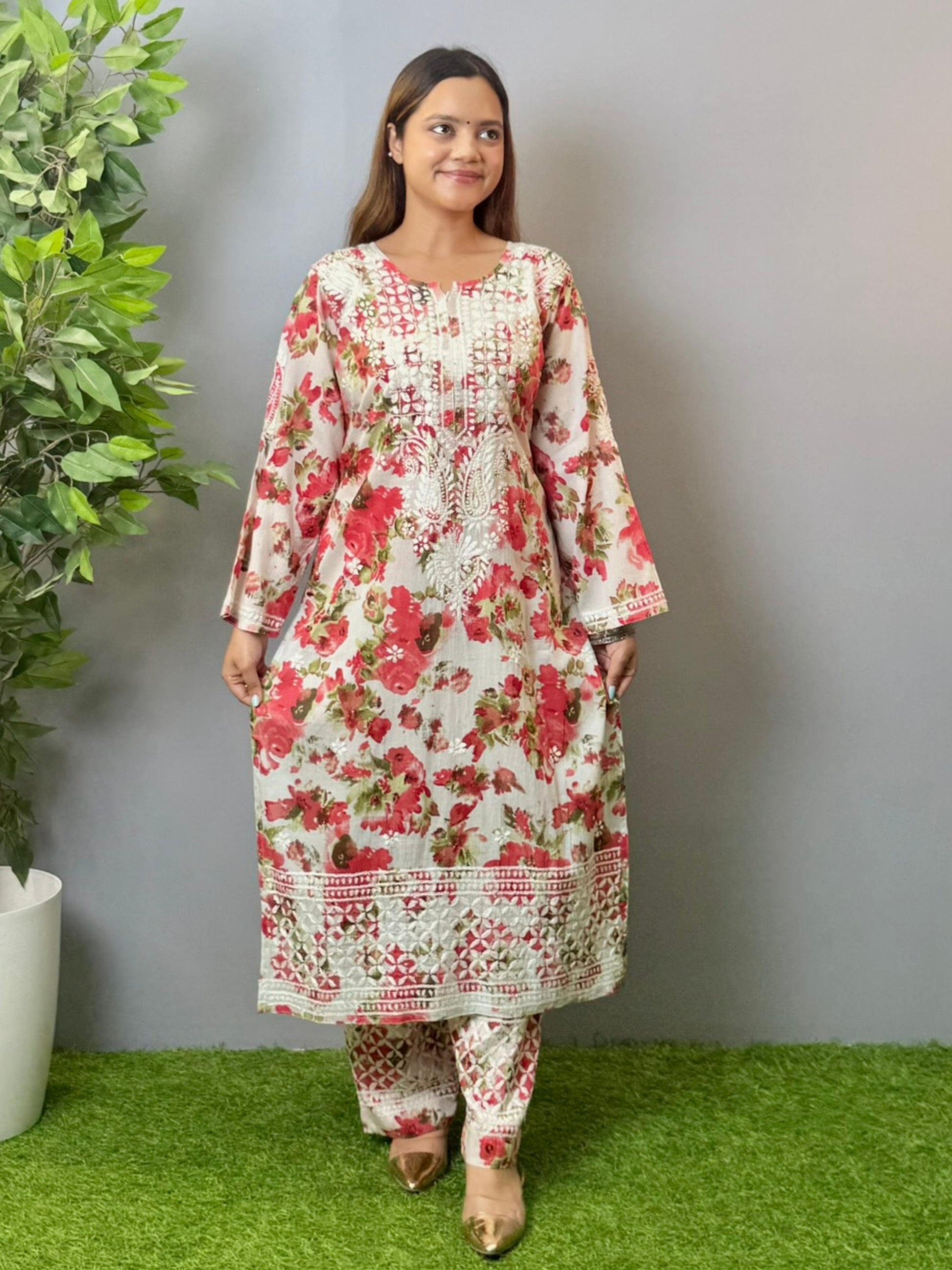 Model wearing floral white mulmul Lucknow chikankari kurta and pant set with pink rose print and white embroidery.
