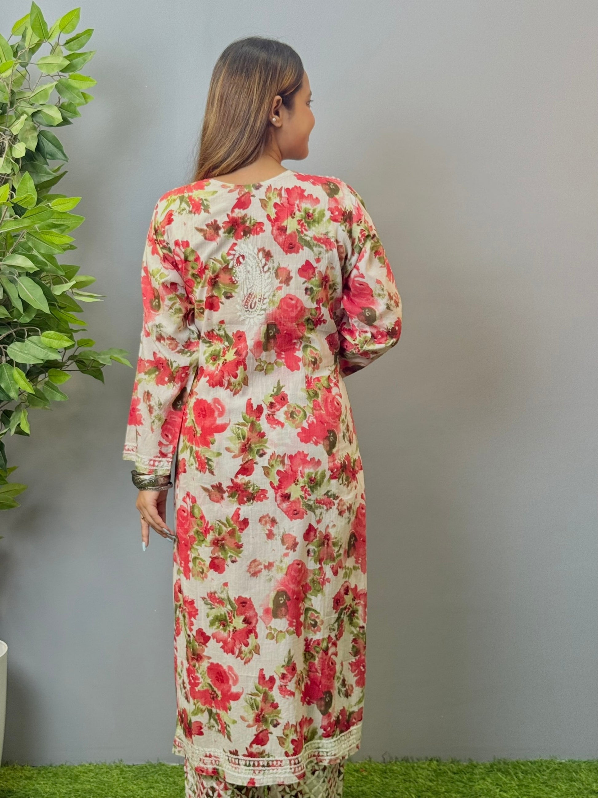 Model wearing floral white mulmul Lucknow chikankari kurta and pant set with pink rose print and white embroidery.