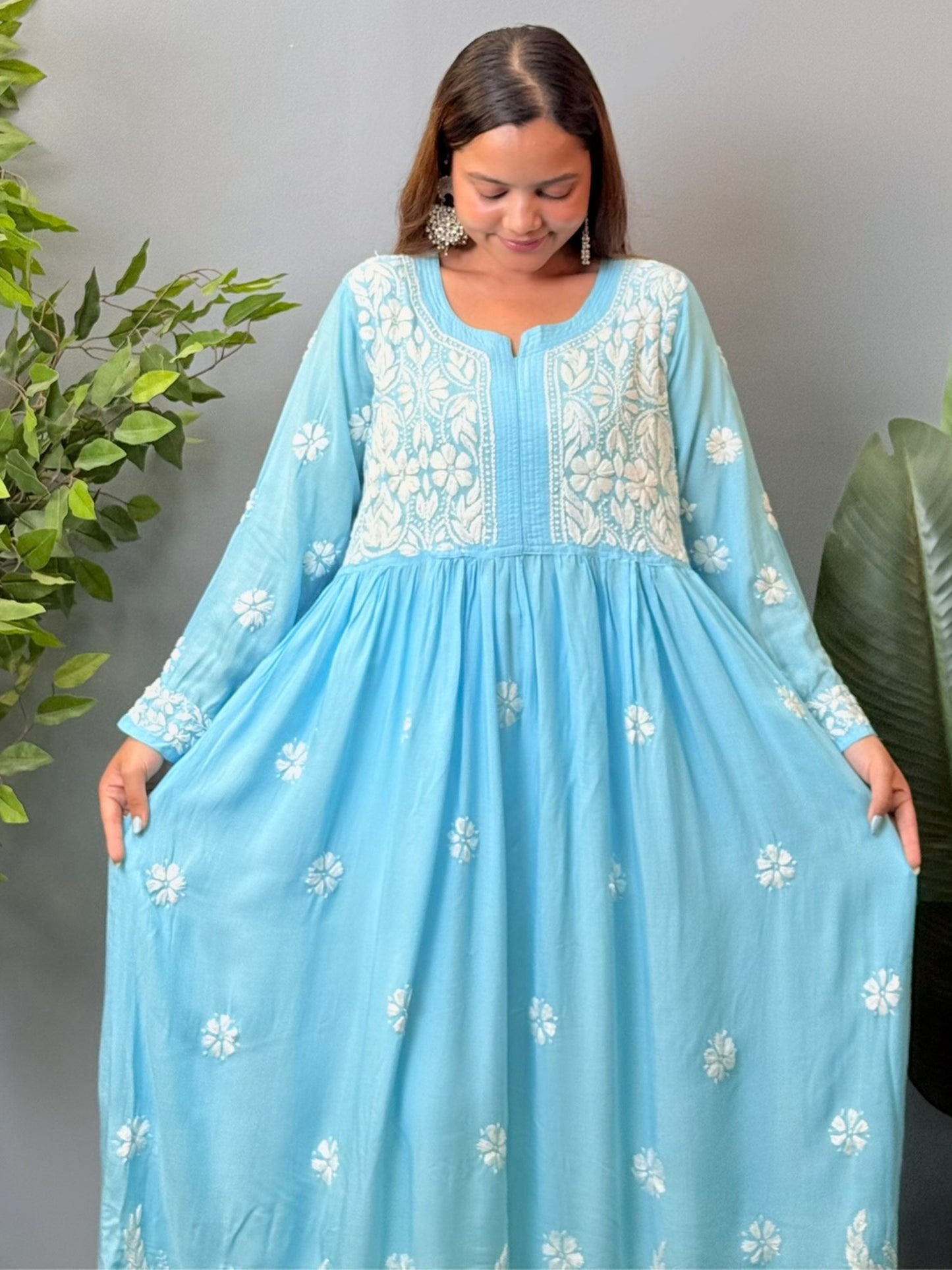 Model wearing a sky blue modal chikankari long frock with white hand embroidery and elegant flared silhouette.