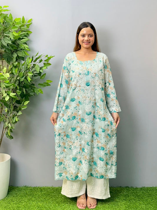 Aqua blue floral printed mulmul chikankari kurta with white embroidery worn by a woman standing on green grass