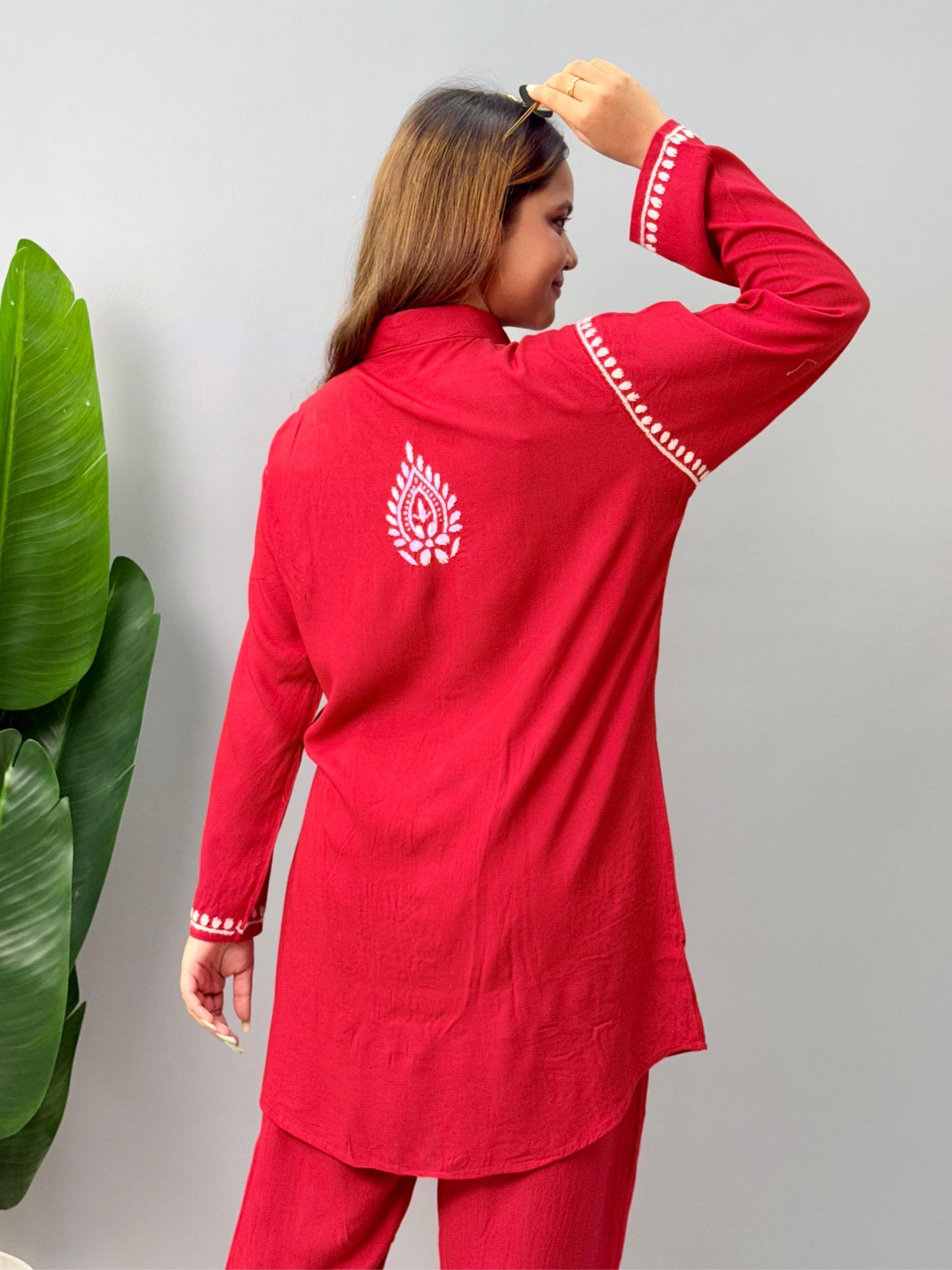 Model wearing a red rayon Lucknowi chikankari co-ord set featuring white hand embroidery on shirt-style kurta and matching pants.